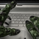 Goblin-like hands stretch out over a laptop's keyboard.